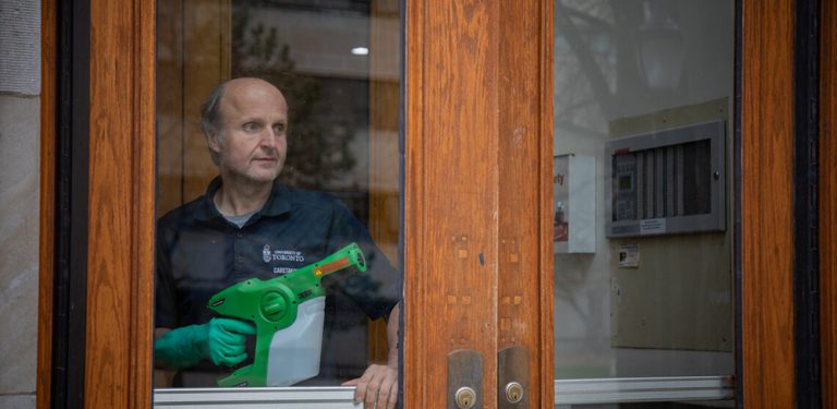 A caretaker uses a spray gun to disinfect surfaces.