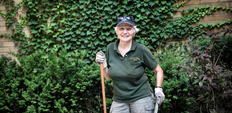 A member of the Grounds team poses for a photo while sweeping.