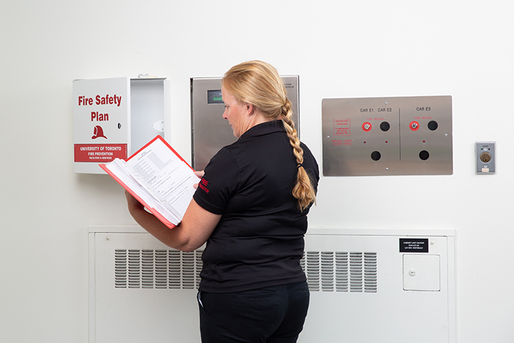 A fire prevention officer looks at a fire safety plan in a building lobby.